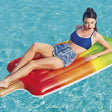 This is a lifestyle image showing a woman posing on this dreamsicle popsicle pool float.
