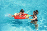 This is a lifestyle image showing a little girl holding onto the handles of the strawberry surf rider while her mom leads her through the water.
