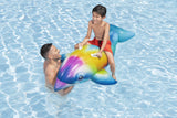 This is a lifestyle image showing a young boy riding on the dolphin float in the water while his dad holds the front of the dolphin.