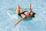 This is a lifestyle image showing a woman resting in the chair in the water. She's smiling toward the camera and putting sunglasses on.
