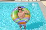 This is a lifestyle image showing a man standing inside a pool holding the inner tube over his head.