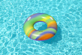 This is a lifestyle image showing the rainbow swim ring resting atop water.