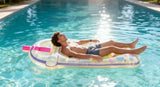 This is a lifestyle image showing a man resting on the pool float in the middle of the pool on a really sunny day.