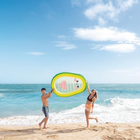 This is a lifestyle image showing two people at the beach holding up the avocado pool float.