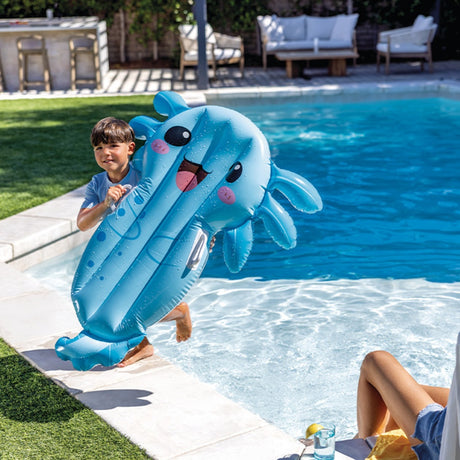 This is a lifestyle image showing a little boy holding the blue axolotl pool inflatable while walking out of the pool.