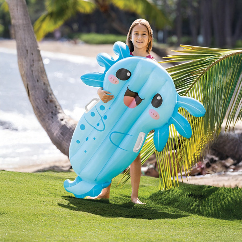 This is a lifestyle image showing a young girl holding the axolotl pool inflatable standing near a palm tree.