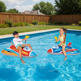This is a lifestyle image showing two young kids on the jet fighter ride ons in a pool. They're both shooting the water blasters at each other.