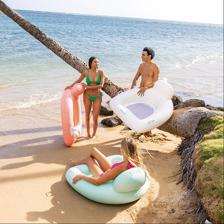 This is a lifestyle image showing three adults on a beach holding these inflatable chairs.