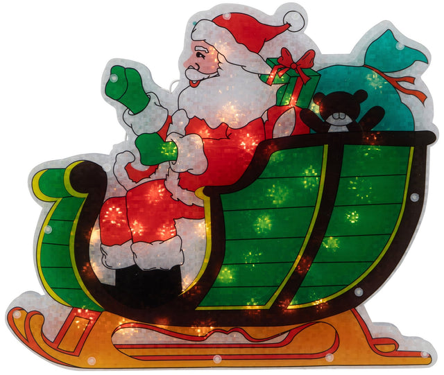 This image shows the Santa in Sleigh decoration on a white background. Santa is wearing his classic red and white suit with green gloves and black boots. He's in a green and black sleigh. There's a teal colored bag of gifts in the trunk of the sleigh. There's also a green and red present and a black teddy bear.