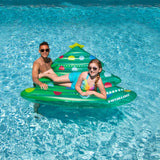 This is a lifestyle image showing a young girl posing and smiling on the float while her dad holds the edge of the float.