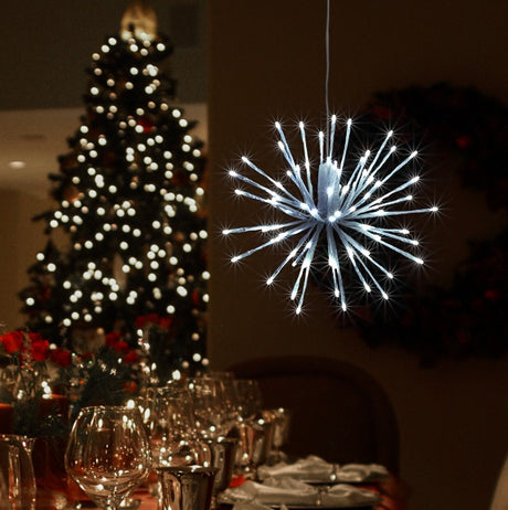 This is a lifestyle image showing the blue and pure white colored light burst hanging from the ceiling in a room decorated for Christmas.
