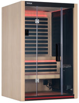A light brown colored home sauna that fits 2 people. There are lights on inside and the lights are red.