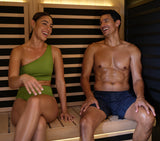 This image shows a woman and a man smiling and laughing inside their home sauna.