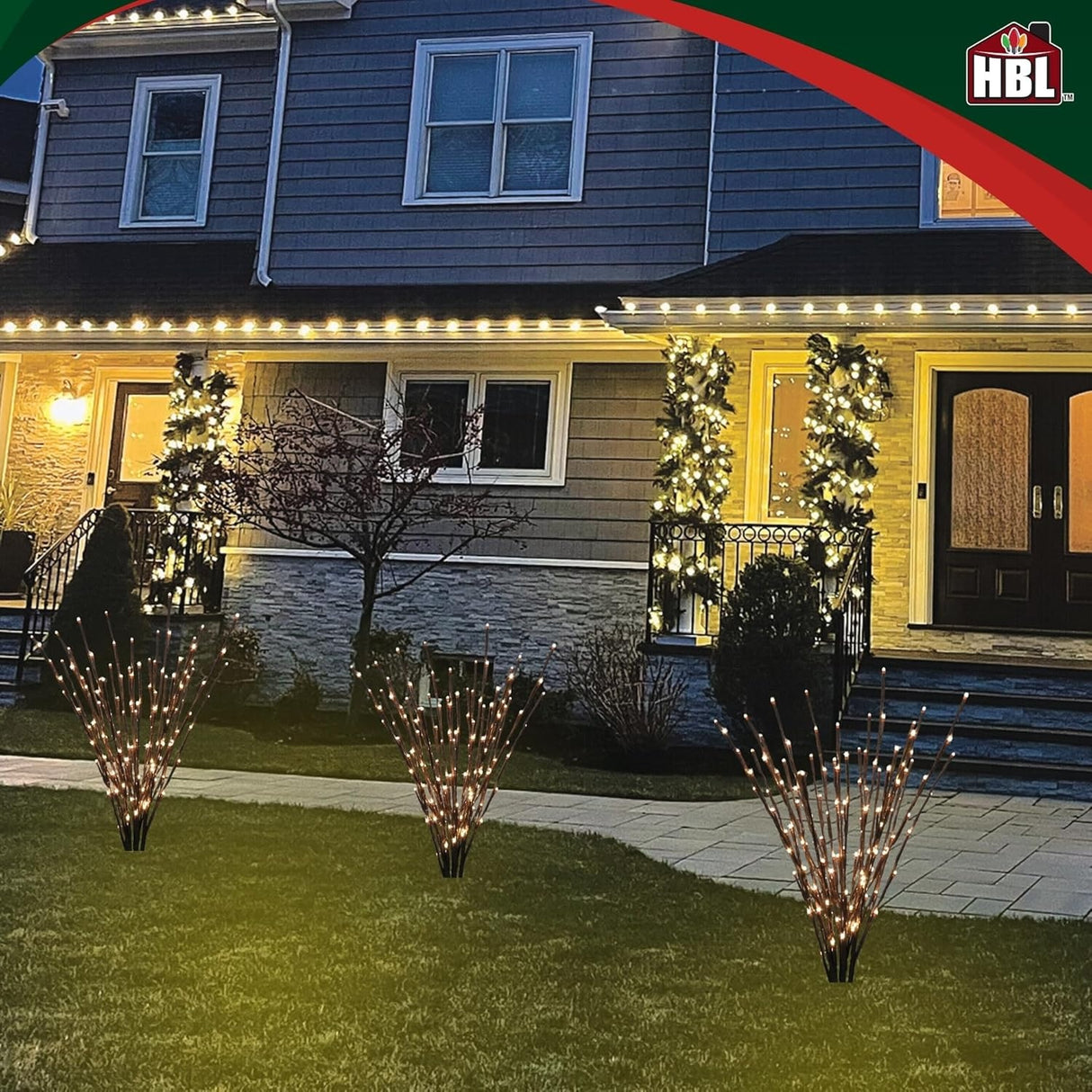 This is a lifestyle image showing three light burst decorations in the yard in front of a house decorated for Christmas.