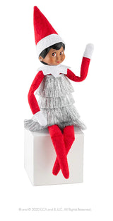 This image shows a Scout Elf wearing the tinsel dress and sitting on a white box.