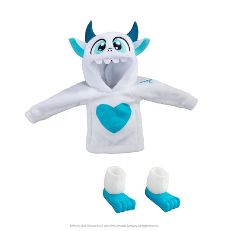 This image shows the Yeti clothes for your Scout Elf on a white background. The hoodie is white with a blue heard on the chest and features ears, horns, eyes, nose and a mouth. It's designed to look like, if you were to put the hood up over your Scout Elf's head, a Yeti monster with blue eyes. There are also two boots designed to make it look like your Scout Elf has blue monster feet.