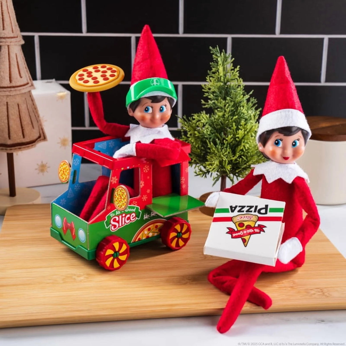 This is a lifestyle image showing a Scout Elf sitting in the pizza truck holding a pizza while another Scout Elf sits next to the truck holding the pizza box.