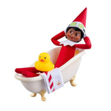 This image shows a Scout Elf on a white background resting in the bathtub with the rubber duck while the towel hangs over the side.