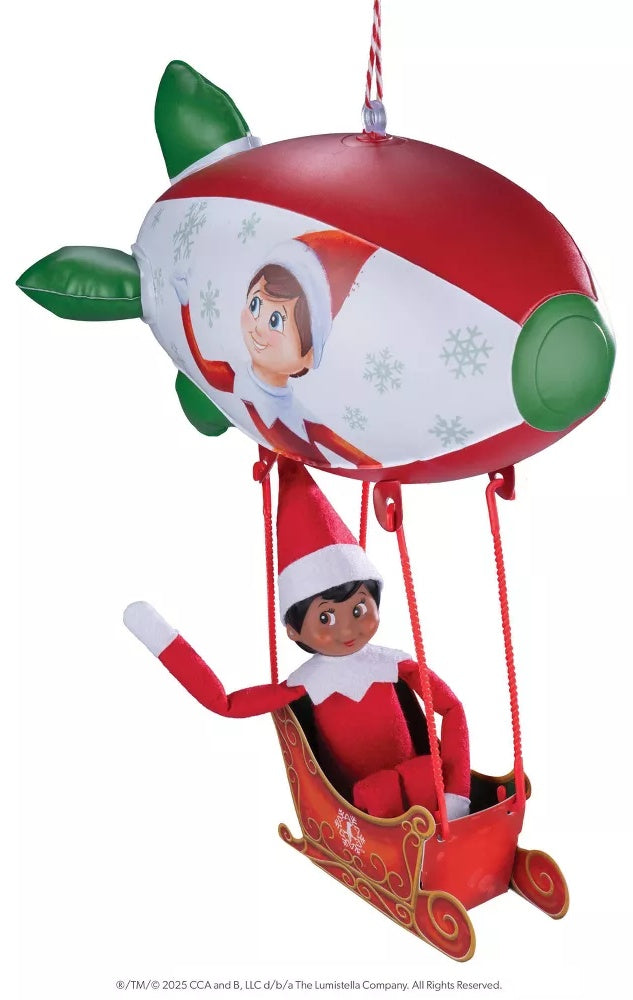 This image shows the Peppermint Blimp on a white background. The blimp is red and white striped with green accents and snowflakes. There's a scout elf on the side. The blimp has a red sleigh attached at the bottom.
