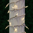 This is a lifestyle image showing these warm white lights on a white wire wrapped around a column outside.