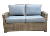 This image shows what this loveseat looks like on a white background. The frame is a tan/brown wicker color. The cushions are a light blue color.