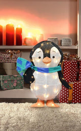 This is a lifestyle image showing Wade the penguin standing in front of some shelves in a living room decorated for Christmas.