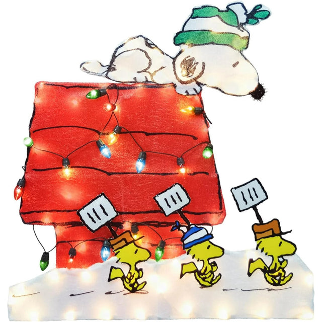 This image shows the decoration on a white background. The decoration features Snoopy wearing a green and white striped winter hat resting atop his red doghouse. Three Woodstock birds are carrying shovels.