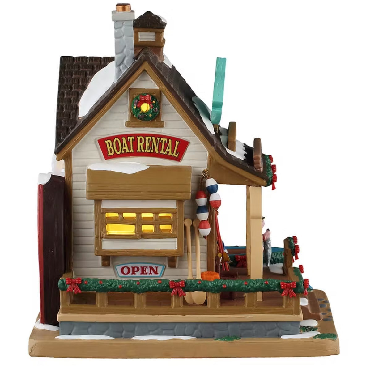 This is the other side of the building. There are signs that read "BOAT RENTAL" and "OPEN." There are oars and fishing rods leaning up against the wall. There are garlands and wreaths decorating the window and the deck.