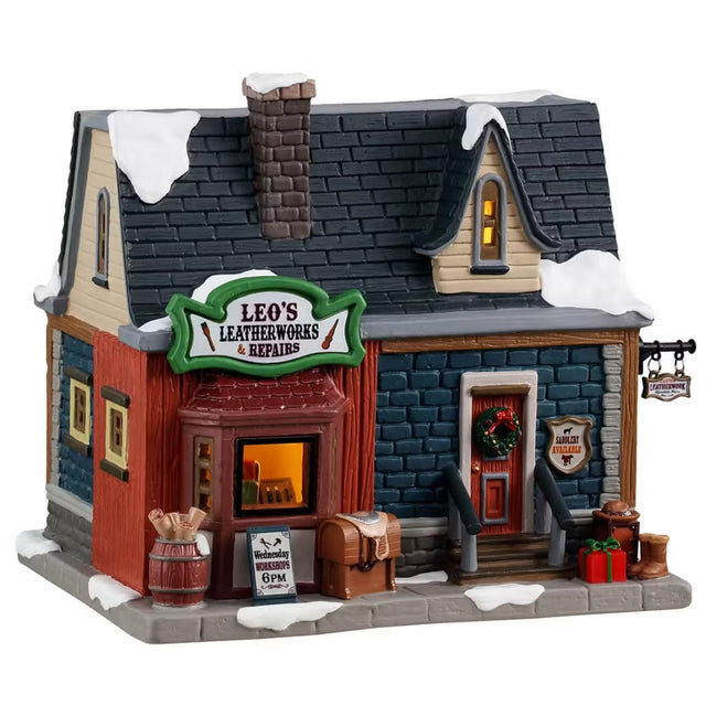 This is a Lemax lighted building designed to look like a small brick building. There's snow on the roof and on the sidewalk. There's a wreath on the red front door. There's a barrel of materials on the sidewalk along with a saddle, a gift and a pair of boots. There's a window in the front and you can see inside.