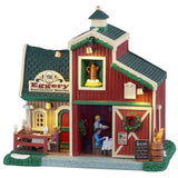 This is a Lemax lighted building designed to look like a barn turned into a breakfast restaurant. There are decorated garlands along the roof and a decorated wreath on the sliding barn door. There's a couple eating at a table on the balcony. Inside the building, there's a waiter bringing a table of people their breakfast. There's some snow on the grass.