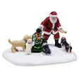 This is a Lemax table accent designed to look like Santa passing out treats and toys to four dogs in the snow.