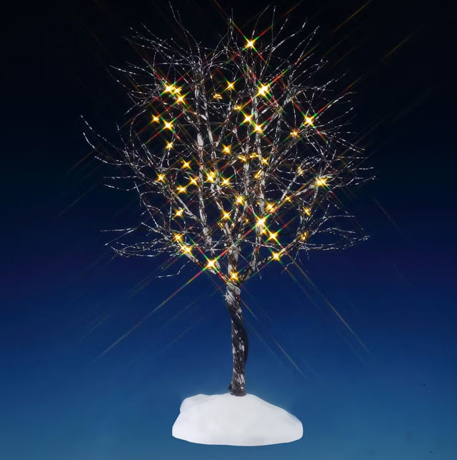 This is a lighted Lemax tree designed to look like a tree with lots of bare branches that are covered in snow. There are lights on some of the branches. This is showing the tree on a blue background.