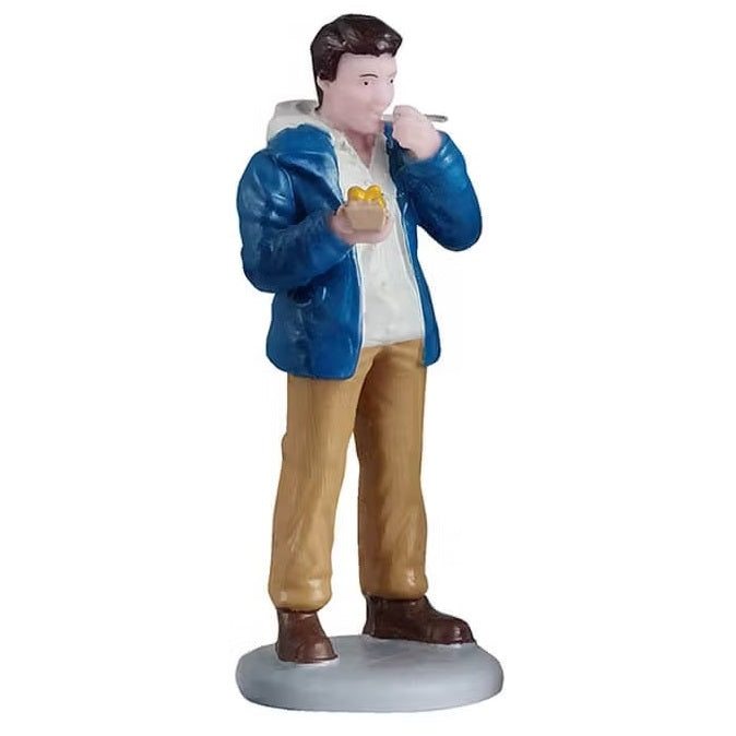 This person is wearing a white hoodie with a blue jacket over it, brown pants and brown shoes. He's using a fork to eat the food he's holding.