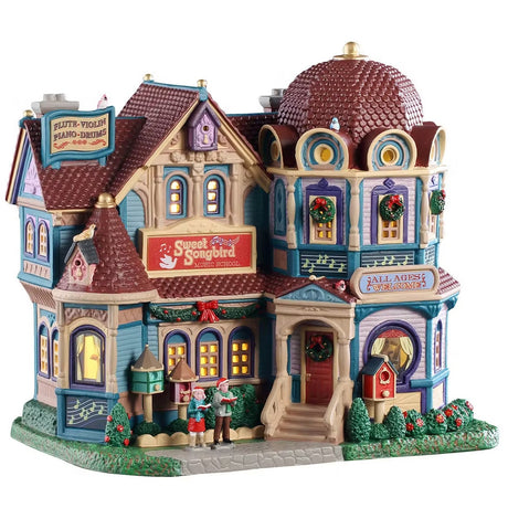 This is a Lemax lighted building designed to look like a very unique mansion turned into a music school. There are lots of intricate details. There's a sign on the roof that reads "FLUTE, VIOLIN, PIANO, DRUMS." The windows are decorated with wreaths. There's a garland hanging above the windows near the front porch. There are two children on the stone sidewalk, they're wearing Santa hats and singing. There's a cute red birdhouse next to a bunch of bushes near the front door.
