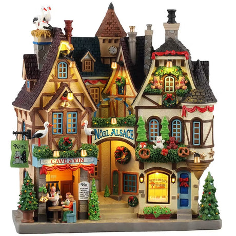 This is a Lemax building façade made up of different shops. There are several pelican birds on the roof. There are garlands and red ribbons and decorated trees everywhere.  