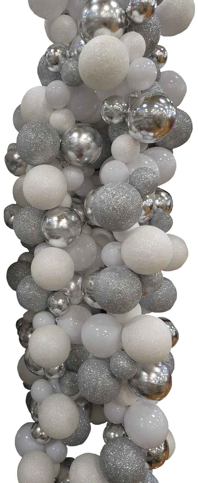 This image shows a beaded garland up against a white background. The beads on the garland consist of different sizes and textures. Some of the beads are covered in white glitter, some of them are a pearlescent white color, some are covered in silver glitter and some are a shiny silver color.