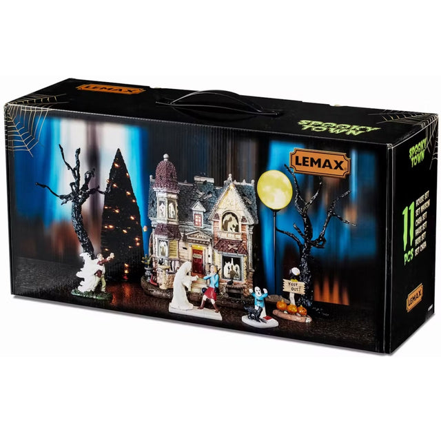 This image shows off the box that this Lemax House Set comes in. It shows the 11 pieces that come with it: three spooky trees, four figurines, one lighted building, one lighted accessory that looks like the moon and two adaptors.