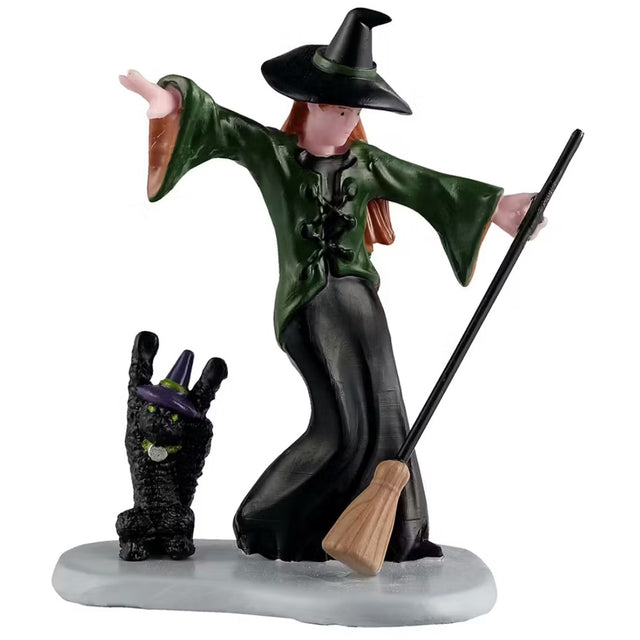 This is a Lemax Spooky Town figurine that's designed to look like a witch and a black cat dancing. The witch is wearing a dark green and black dress and matching pointy hat. She's holding a broom. Her cat is wearing a dark purple and green pointy hat, a collar and has glowing green eyes.