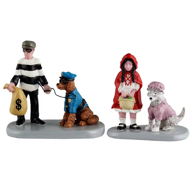 This image shows two Lemax Spooky Town figurines. One figurine shows a young boy dressed as a robber, wearing a black eye mask, a white and black striped sweater and he's holding a brown bag with a dollar sign on it. He's holding a leash attached to a dog who is dressed up as a cop. The dog is wearing a blue police uniform and sunglasses. The other figurine shows a young girl dressed as Little Red Riding Hood carrying a basket of food. Next to her is a dog dressed up like Little Red Riding Hood's grandma.