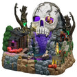 This is a Lemax Spooky Town table accent designed to look like a lagoon hidden among a bunch of rocks and boulders. There's a rundown shack on the left with a bunch of jack-o-lanterns next to it. There are two trees with glowing faces on them. The entrance to the cave is shaped like a big skull with purple eyes.