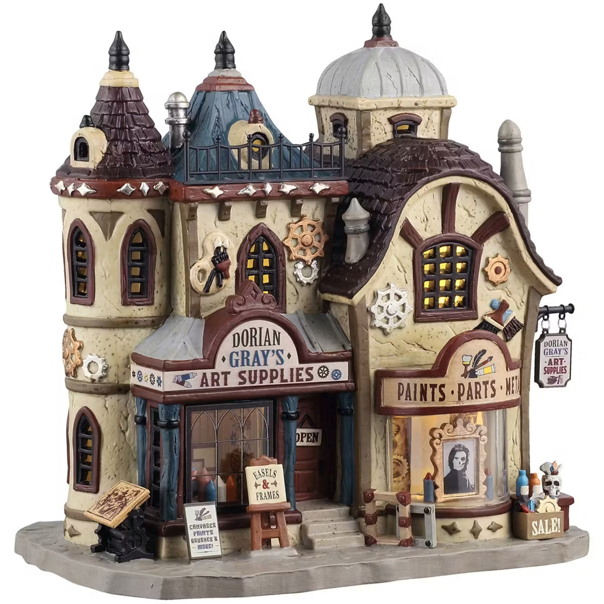 This is a Lemax Spooky Town building designed to look like an old-timey mansion. The sign over the front door reads "DORIAN GRAY'S ART SUPPLIES." On the sidewalk, there are signs that read "CANVASES, PRINTS, BRUSHES & MORE!" and "EASELS & FRAMES." Inside the window on the left of the front door, you can see a bunch of different colored crayons. Inside the window on the right of the front door, there's a portrait of a woman but half of her face is a skeleton.