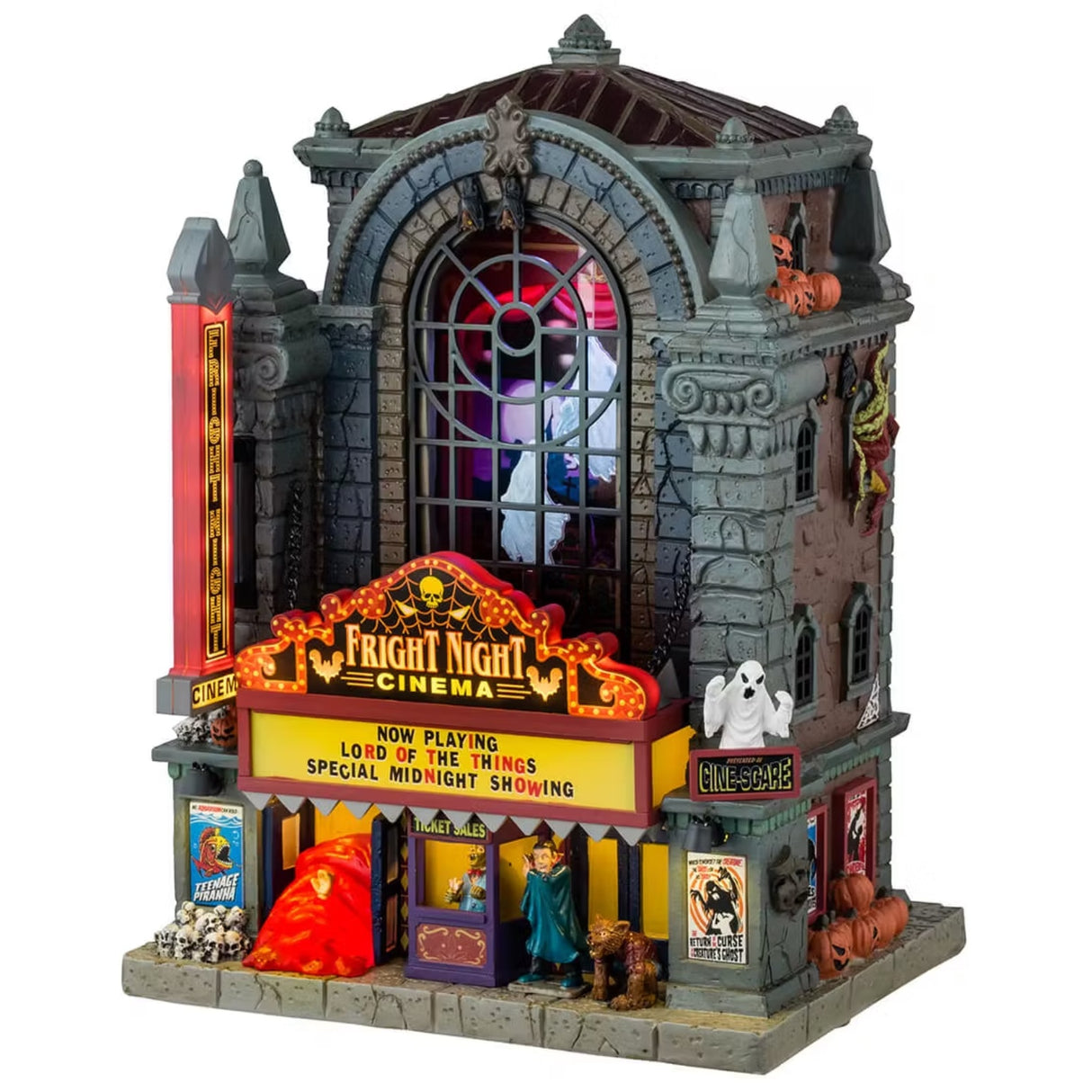This is a Lemax Spooky Town lighted building that's designed to look like a tall, gothic building that's been turned into a movie theater. It's called Fright Night Cinema. There are ghosts visible through the big window in the front. Underneath the marquee, there are skulls and a vampire standing next to a werewolf.