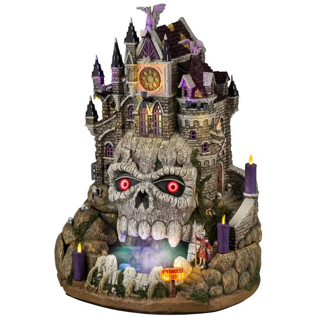 This is a Lemax Spooky Town Sights and Sounds building designed to look like an old, gothic castle built into a rocky hill. The front of the building has a cave that looks like a skull with red, glowing eyes. Smoke comes out of the mouth of the cave.