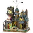 This is a Lemax Spooky Town building designed to look like a semi-rundown mansion. There's a sign that reads "SPELLS ABOUND." There are three bats flying above. There's a big wizard statue over one of the doors. You can see a wizard casting a spell on a cauldron, a person carrying books and a black cat on the sidewalk.