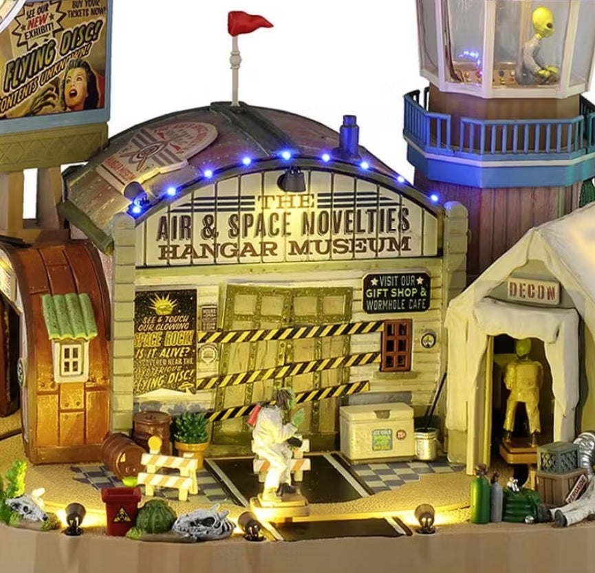 This is an up close view of this building. There are people in white suits walking around and an alien at the top in the control room.