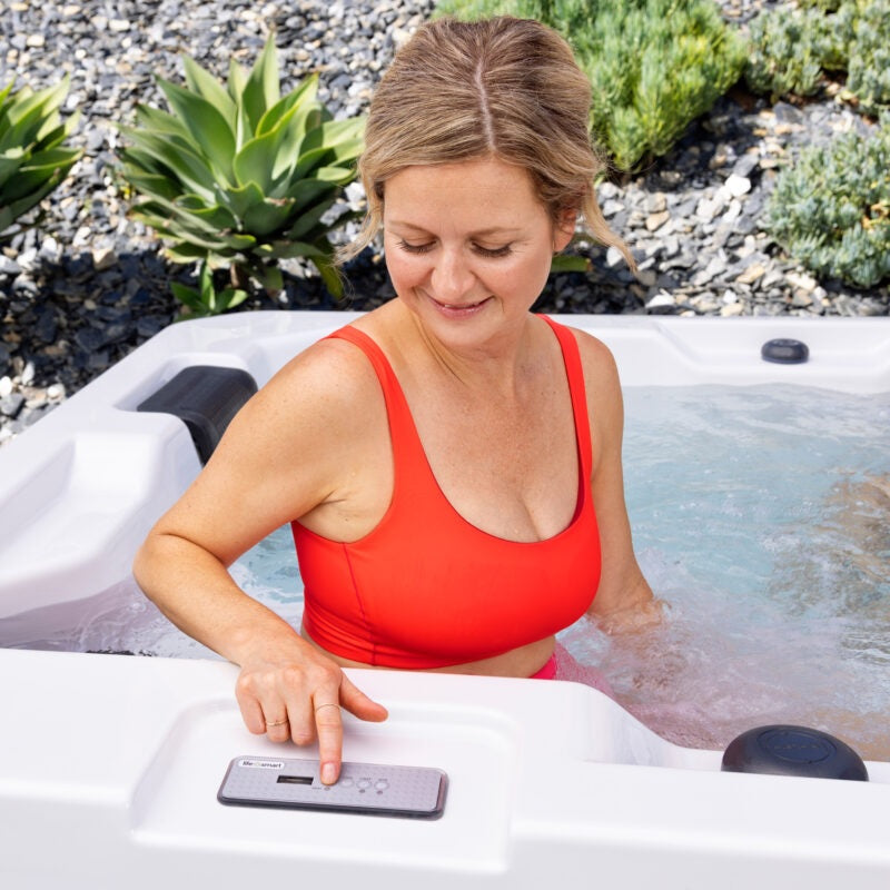 This is a lifestyle image of a woman adjusting the jets using the control panel on the side of the hot tub.