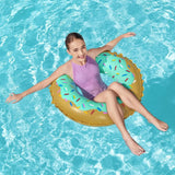 This is a lifestyle image showing a young girl sitting in the inner tube in a pool, smiling up at the camera.