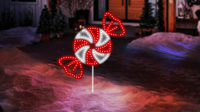 This moving image shows the peppermint candy LED light on a stake in front of a house on a snowy night.