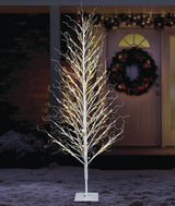 This is a lifestyle image showing the birch tree on the snowy lawn in front of a house.