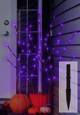 This is a lifestyle image showing the three branches inside of an orange flower pot on a porch near a front door. There's also a picture of one of the black ground stakes so you can see what they look like.